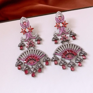 Macro detail of bohemian fan-shaped drop earrings with red gems and fringe tassels