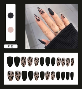 Detail view of R153 matte almond press-on nails with black and cow print designs