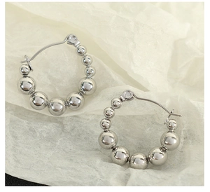 Detailed close-up of beaded silver hoop earrings on elegant textured paper background