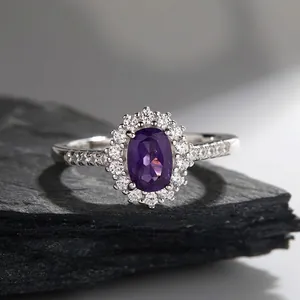 Macro shot of oval amethyst ring with halo of white zircons on natural stone background
