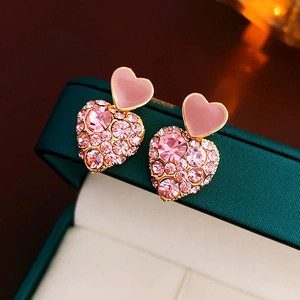 Macro shot of gold-plated pink heart stud earrings with sparkling crystal pavé details