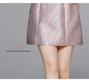 Détail de la robe vintage rose avec tissu jacquard métallique et ourlet plissé élégant