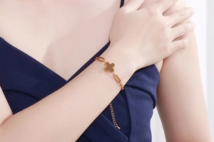 Close-up of gold cross pendant bracelet with rectangular links on model's wrist