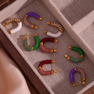 Detailed macro view of U-shaped gold-plated earrings with colorful enamel and zircon insets