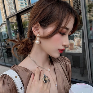 Detail of elegant gold double-layered star necklace and pearl earrings on a female model