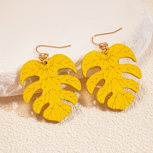 Macro detail of tropical yellow monstera leaf earrings with etched veins and gold fishhook