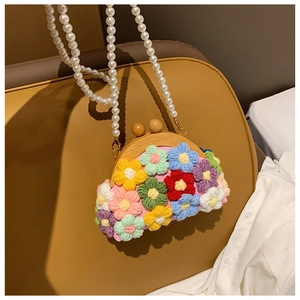 Detail of pink hand-woven shell bag featuring colorful 3D floral accents and pearl strap