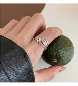 Detail of layered silver minimalist rings worn on index finger with a creative aesthetic