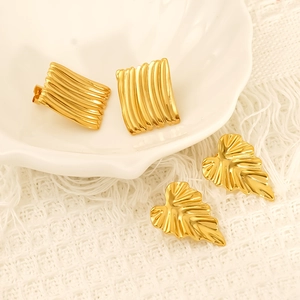 Detailed close-up of golden curved leaf earrings and square wave textured metal jewelry