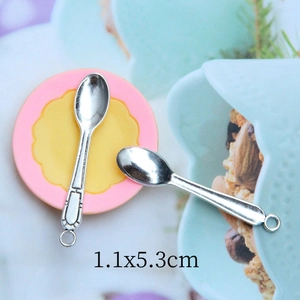 Macro detail of miniature alloy spoon charm with hanging loop for dollhouse DIY crafts