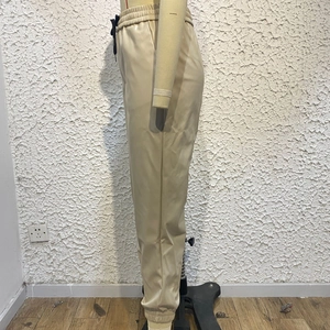 Dettaglio dei pantaloni jogger in ecopelle beige con coulisse ed orlo elastico