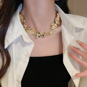 Close-up of a gold irregular textured metal necklace worn on a model with white shirt
