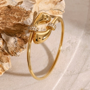 Macro-opname van een gouden druppelarmband met kristallen op natuursteen achtergrond