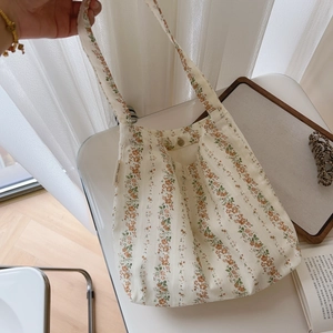 Detail of floral cotton hobo bag featuring metal snap button and brand woven label