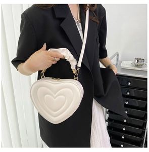 Close-up of cream heart-shaped PU leather bag with quilted pattern and pleated handle