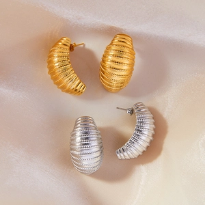 Textured geometric C-shaped hoop earrings in gold and silver finish on silk fabric