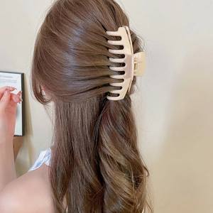 Detail of a large milk tea beige matte hair claw clip styled on a model in a bun