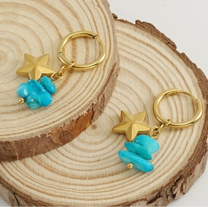 Detail of star-shaped golden earrings with natural blue stone beads on wooden base