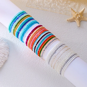 Colorful seed bead bracelet set displayed on a white stand with a beach aesthetic