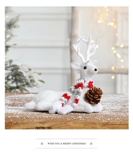 White reindeer Christmas ornament with a knitted scarf and natural pinecone on snowy wood