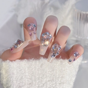 Luxury nude press-on nails with multi-faceted diamonds and star rhinestones on model hands