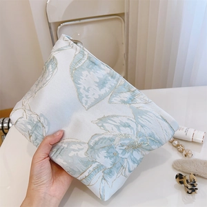 Gros plan détaillé d'une trousse à maquillage jacquard bleue avec fermeture éclair argent