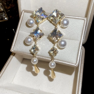 Macro detail of diamond-cut crystals and white pearls on gold-tone drop earrings