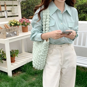 Outdoor shot of mint green puff cloud shoulder bag paired with matching linen shirt