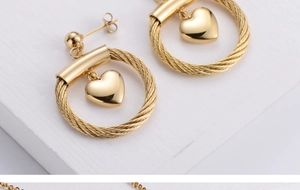 Detailed close-up of golden heart pendant earrings with twisted rope texture rings