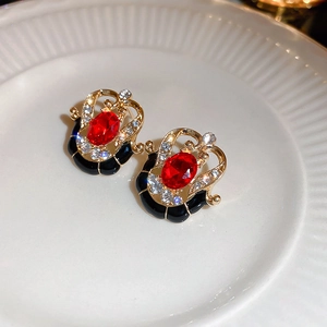 Macro view of gold-tone geometric earrings with red gemstone and black enamel inlay