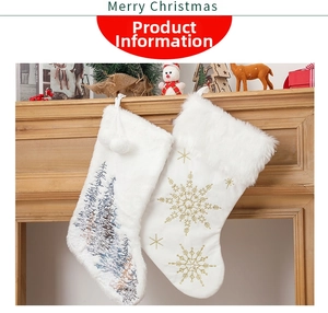 Detail of white plush Christmas stockings with tree and snowflake embroidery hanging on mantel