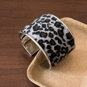 Détail d'un bracelet ouvert argenté avec motif léopard floqué sur un plateau beige