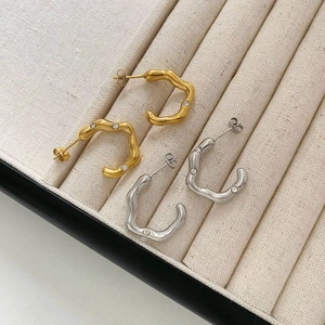 Detail of C-shaped gold and silver wave earrings with inset diamonds on display tray