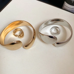 Detailed view of polished gold and silver oval bangles with matching wide open rings