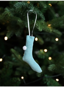 Detailed close-up of a teal knitted Christmas stocking with a white pompom and ribbon