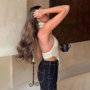 Dettaglio del top bianco in maglia con scollo all'americana e design senza schienale