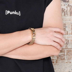 Detail of gold rock hip-hop chain bracelet worn by a model on a textured background