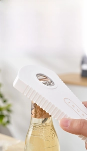 Close-up of a white multifunctional plastic jar opener showing beer bottle opener function