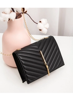 Detail of black chevron quilted crossbody bag with gold tassel and elegant chain strap