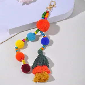 Dettaglio portachiavi boho con pompon colorati, nappe e perline in legno