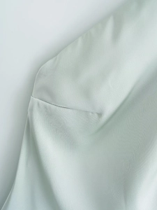Close-up of fine sewing craft and smooth satin texture on pale mint green dress