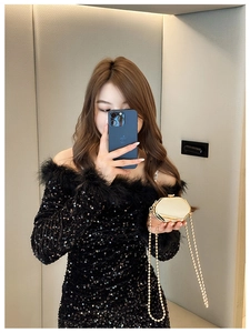 Chic gold hexagonal mini metal chain bag styled with a black sequin feather dress
