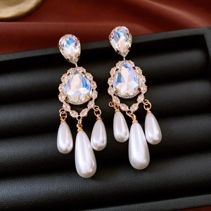 Detailed close-up of 18k gold-plated drop earrings with crystals and white pearls