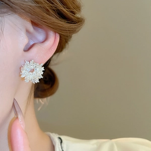 Close-up of snowflake zircon earrings with a pearl center on a model's ear
