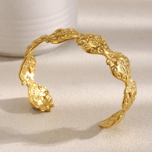 Detailed view of the 18K gold plated strawberry textured bangle in a relief design