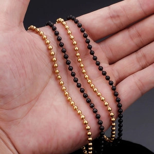 Macro shot of gold and black stainless steel ball chains held in hand for detail