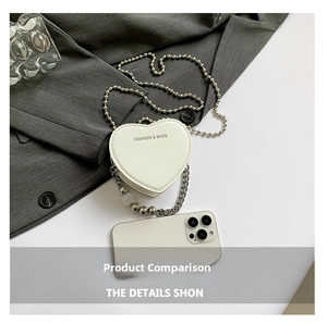 Close-up of mini white heart-shaped PU leather bag with metal chains and pearl beads