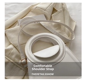 Detail of white leather handbag with adjustable strap and large round hollow metal handle