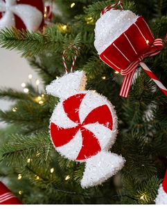 Macro shot of red and white swirl candy and cupcake ornaments with festive glitter on a tree