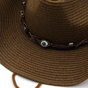 Detail of woven straw cowboy hat with evil eye charm and vintage metal beads